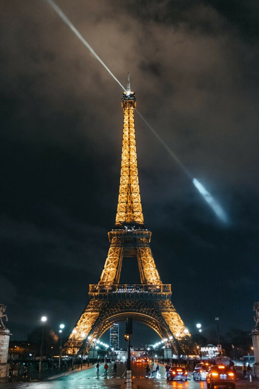 Experience the magic and romance of Paris at night with our canvas print of a photograph featuring the iconic Eiffel Tower illuminated against the night sky, with the light at the top of the tower casting a warm glow on the clouds above. This stunning piece of art captures the enchanting beauty and timeless elegance of one of the most recognizable landmarks in the world, making it the perfect addition for any lover of travel, architecture, and the city of lights.