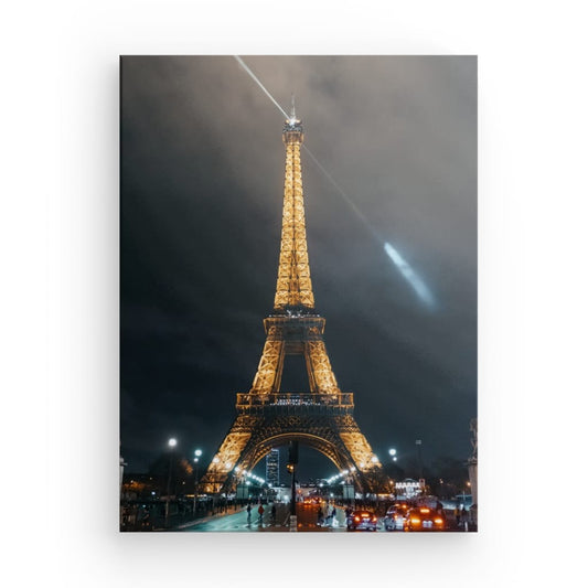 Experience the magic and romance of Paris at night with our canvas print of a photograph featuring the iconic Eiffel Tower illuminated against the night sky, with the light at the top of the tower casting a warm glow on the clouds above. This stunning piece of art captures the enchanting beauty and timeless elegance of one of the most recognizable landmarks in the world, making it the perfect addition for any lover of travel, architecture, and the city of lights.